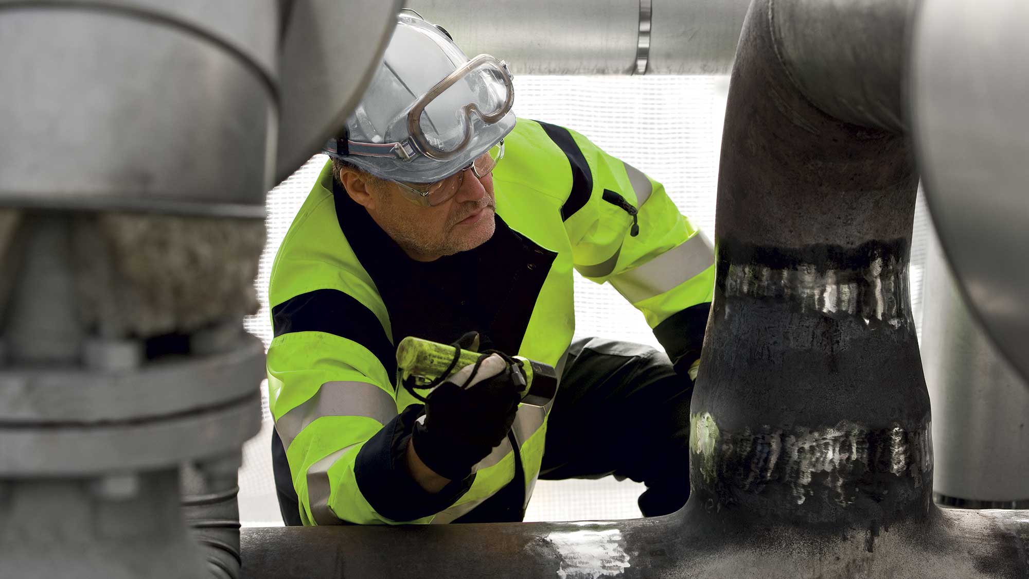 Arbetare inspekterar rör och industripipor i en teknisk anläggning.