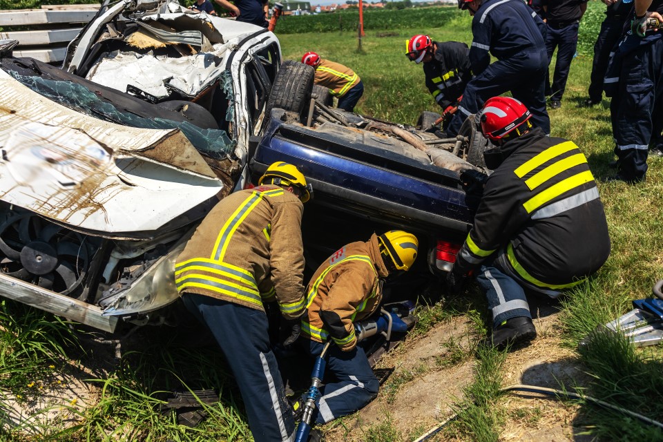 Brandweerlieden in uniform werken samen bij een verkeersongeval met twee zwaar beschadigde voertuigen