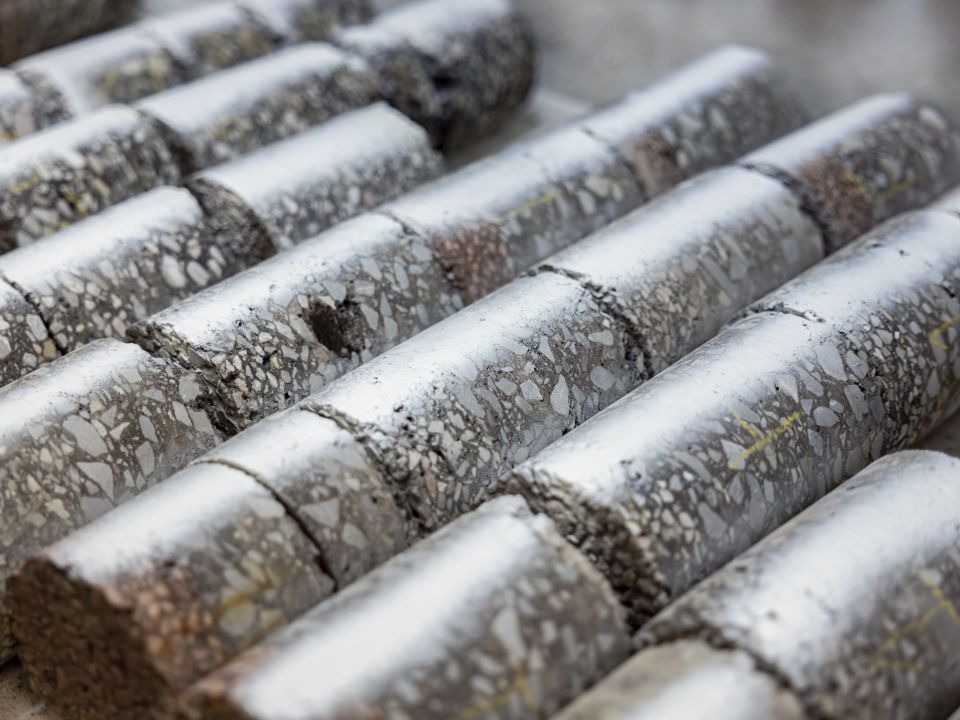 Rijen cilindrische betonmonsters met zichtbare aggregaatstructuur.