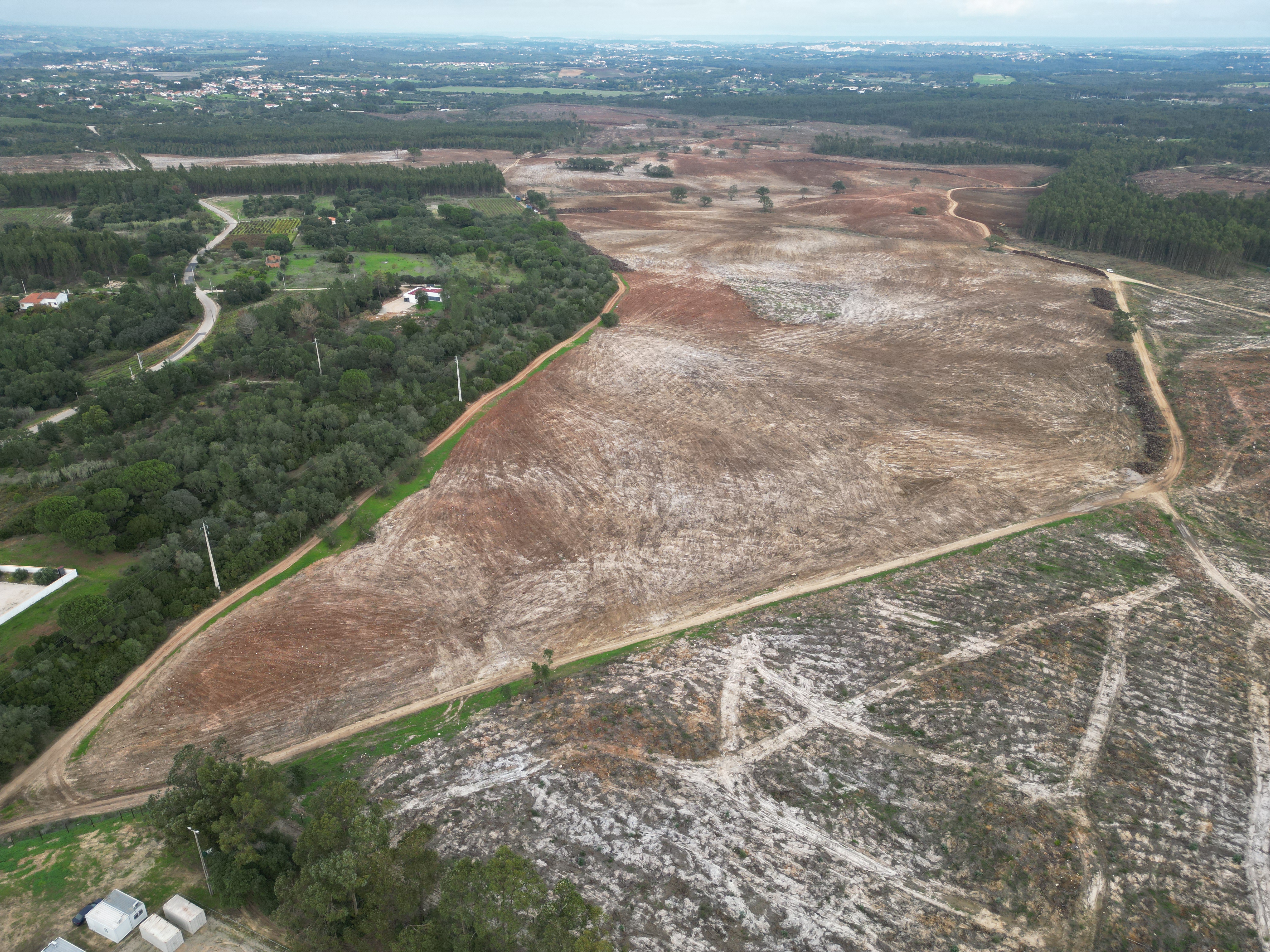 Aerial view of a deforested landscape with patches of dry, bare soil and surrounding green forested areas, highlighting environmental impact and land use changes
